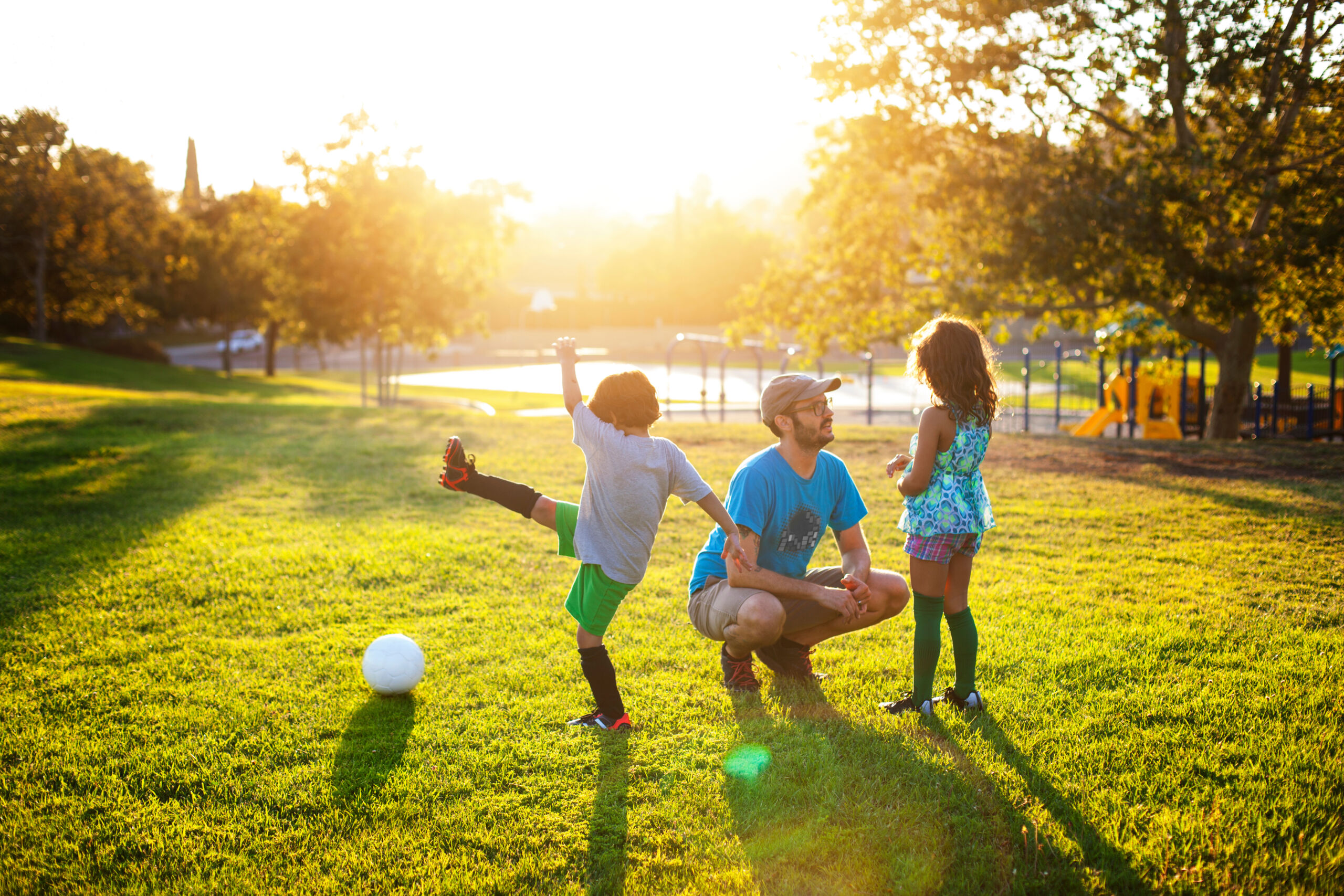 Family playing on grassy field at park during sunset